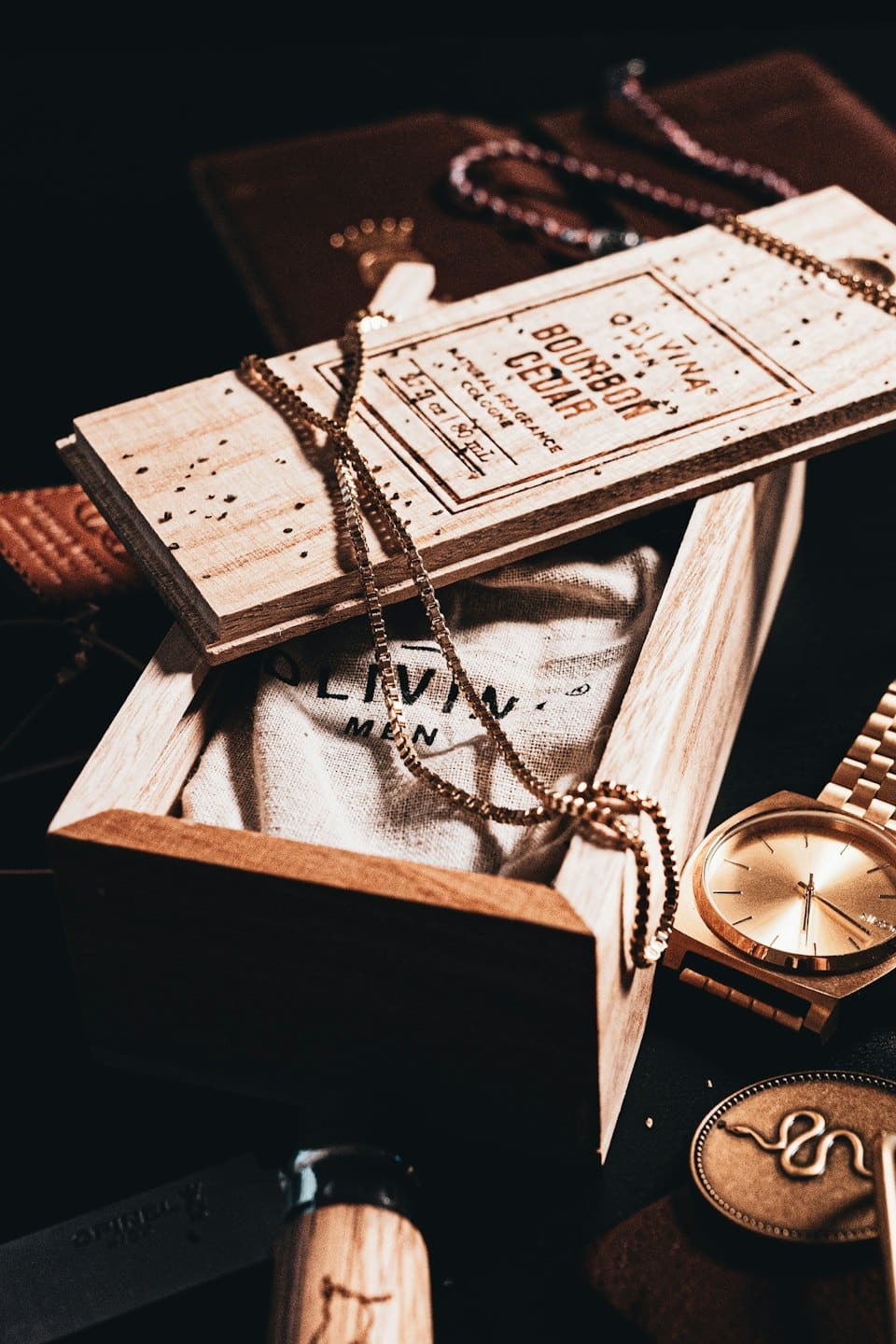 Gold watch, chain, cologne box, and pocket knife arranged stylishly.