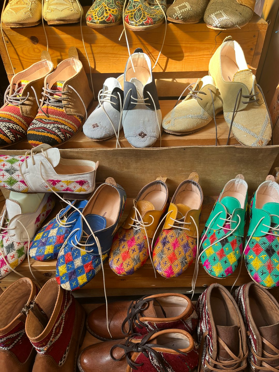 Handcrafted lace-up shoes sit displayed on rustic wooden shelves.